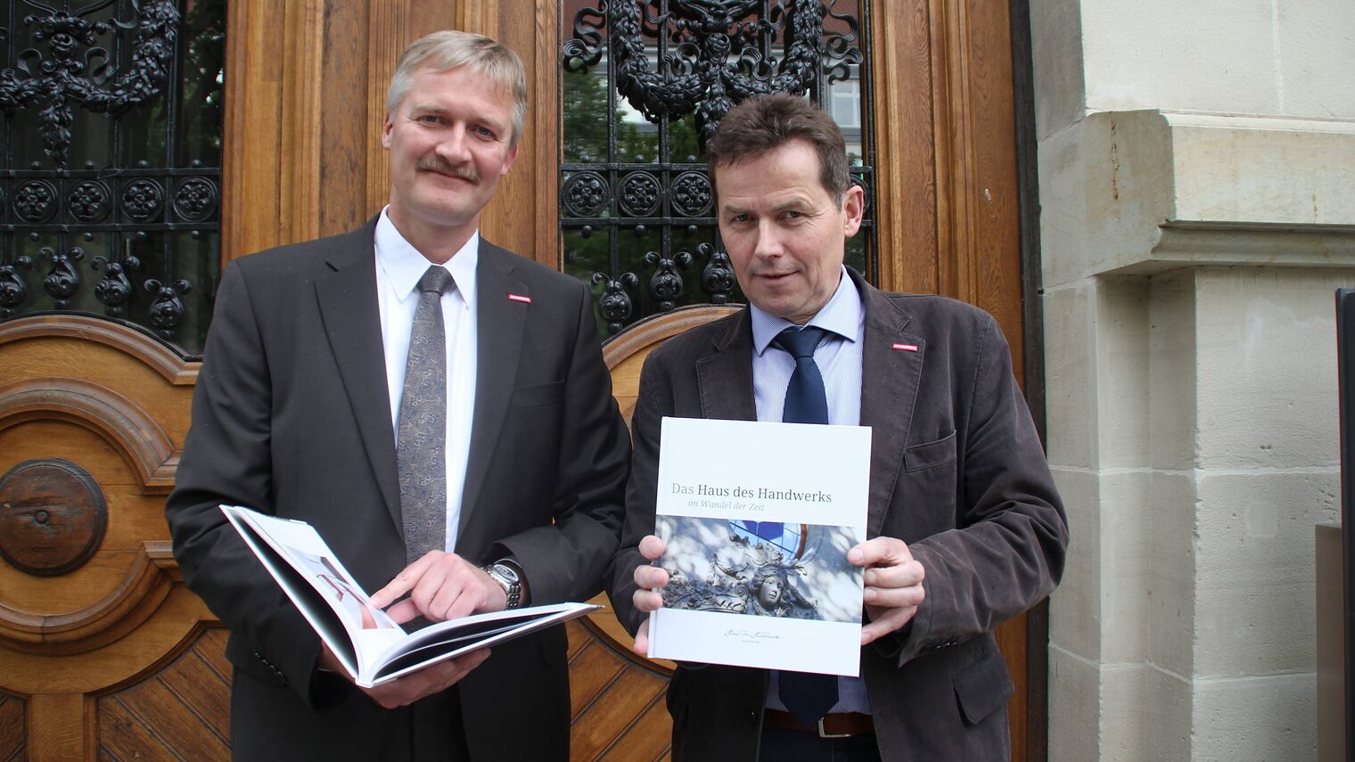 Handwerkskammer-Präsident Hagen Mauer (rechts) und Hauptgeschäftsführer Burghard Grupe präsentieren das Buch "Das Haus des Handwerks im Wandel der Zeit".
