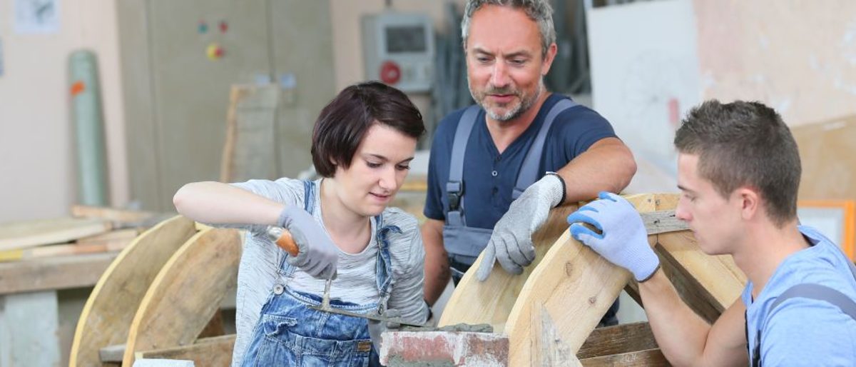 Ausbilder zeigt Azubis wie man mauert