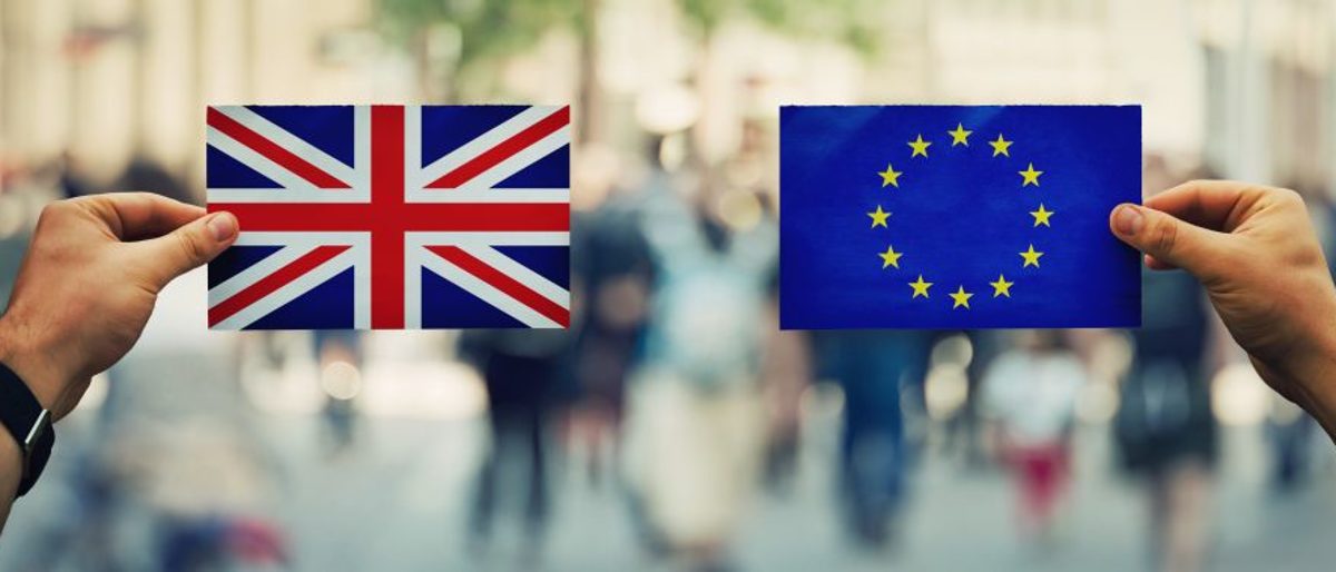 Zwei Hände halten je eine Europa- und eine Großbritannien-Flagge