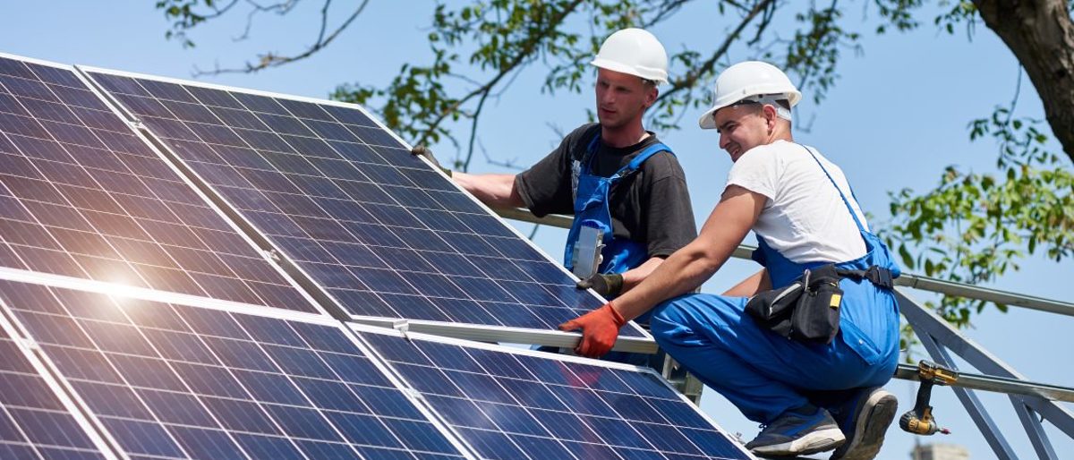 Zwei Techniker installieren Photovoltaik Paneele.