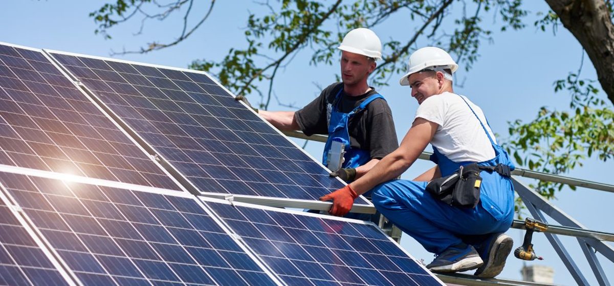 Zwei Techniker installieren Photovoltaik Paneele.