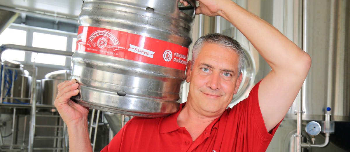 Der Unternehmer Ulf Steinforth hat in Magdeburg-Sudenburg die Brau-Tradition wiederbelebt. Unternehmer Ulf Steinforth trägt ein Bierfass auf der Schulter