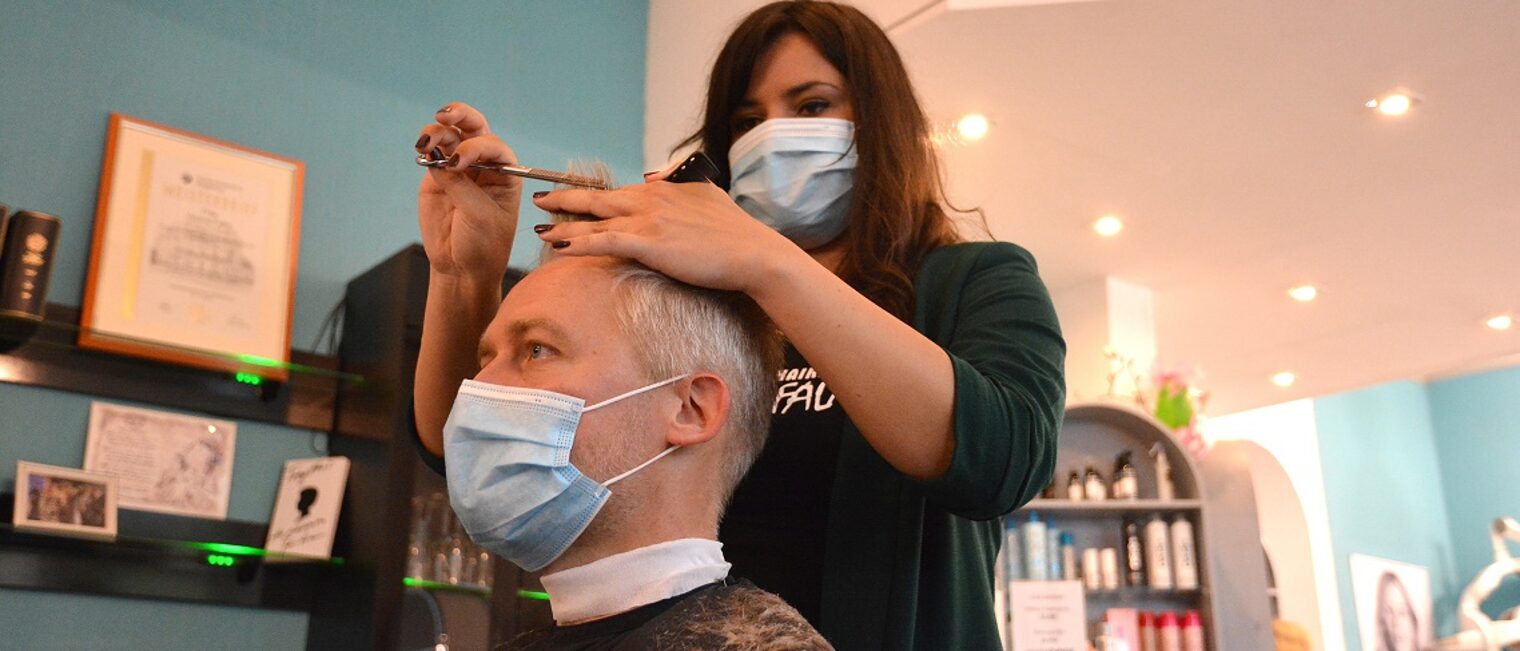 Friseurmeisterin Verena Falke schneidet Handwerkskammer-Hauptgeschäftsführer Burghard Grupe die Haare.