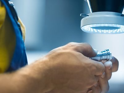 Engineer in a factory is inspecting a metal detail under a microscope with flashlight. Schlagwort(e): accuracy, accurate, caliper, check, checking, closeup, control, coordinate, detail, development, device, equipment, factory, hand, inch, industrial, industry, inspection, inspector, instrument, laborer, light, machine, male, man, manufacture, manufacturing, measurement, metal, metalwork, microscope, parts, person, precise, precision, probe, production, quality, steel, technology, tool, work, worker, workman, workplace, workshop, accuracy, accurate, caliper, check, checking, closeup, control, coordinate, detail, development, device, equipment, factory, hand, inch, industrial, industry, inspection, inspector, instrument, laborer, light, machine, male, man, manufacture, manufacturing, measurement, metal, metalwork, microscope, parts, person, precise, precision, probe, production, quality, steel, technology, tool, work, worker, workman, workplace, workshop