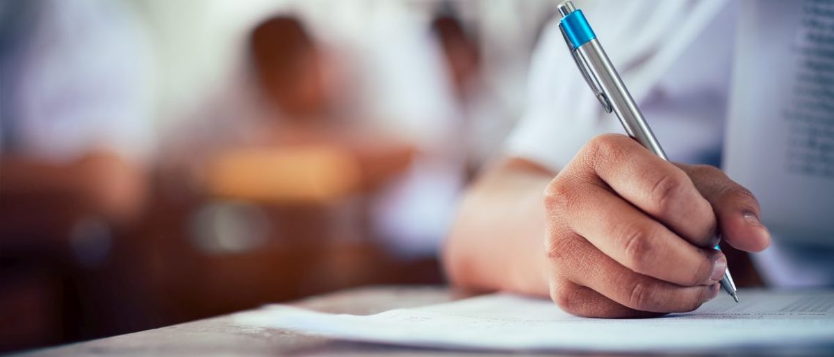 Hand eines Schüler hält Stift bei Prüfung