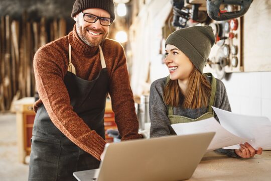 Mann und Frau in einer Werkstatt. Sie arbeiten an einem PC.