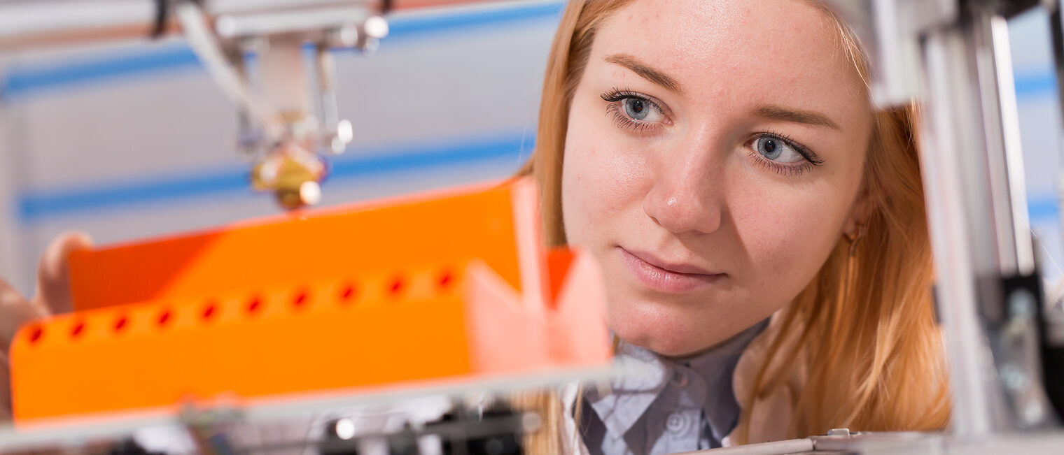 A female student or laboratory assistant in the automation laboratory is debugging the work of the 3d printer. 3d printer is a device for modeling 3D objects